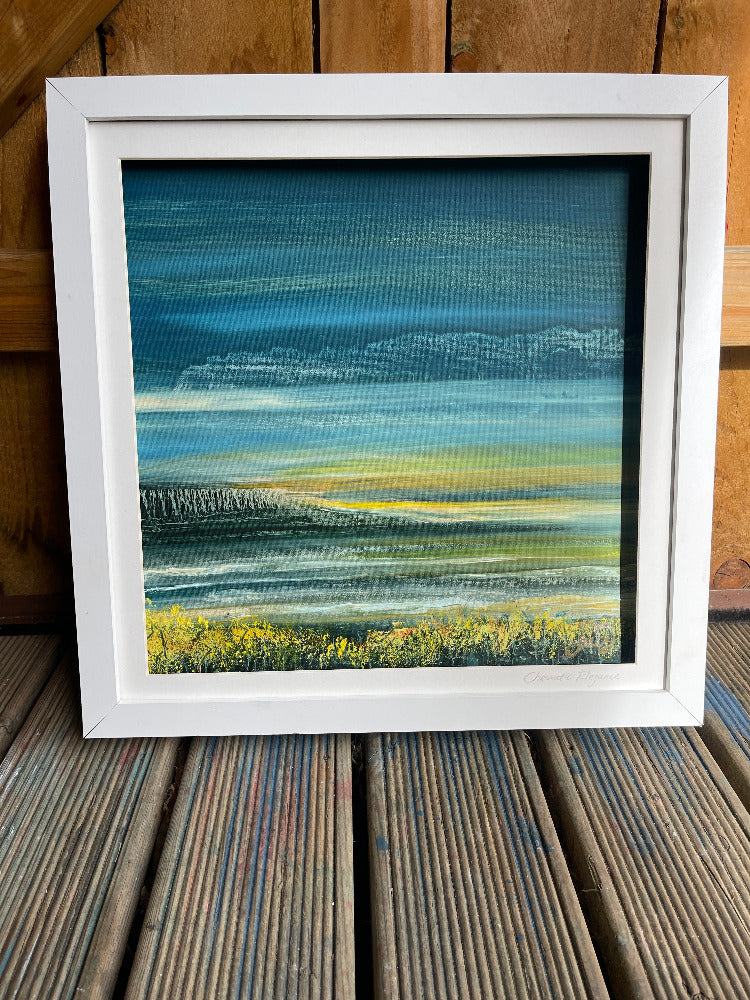 Framed abstract painting with blue, green, and yellow colors on a wooden surface